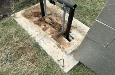 Outdoor natural gas meter piping and shut-off valve installation on a concrete utility pad beside a building.